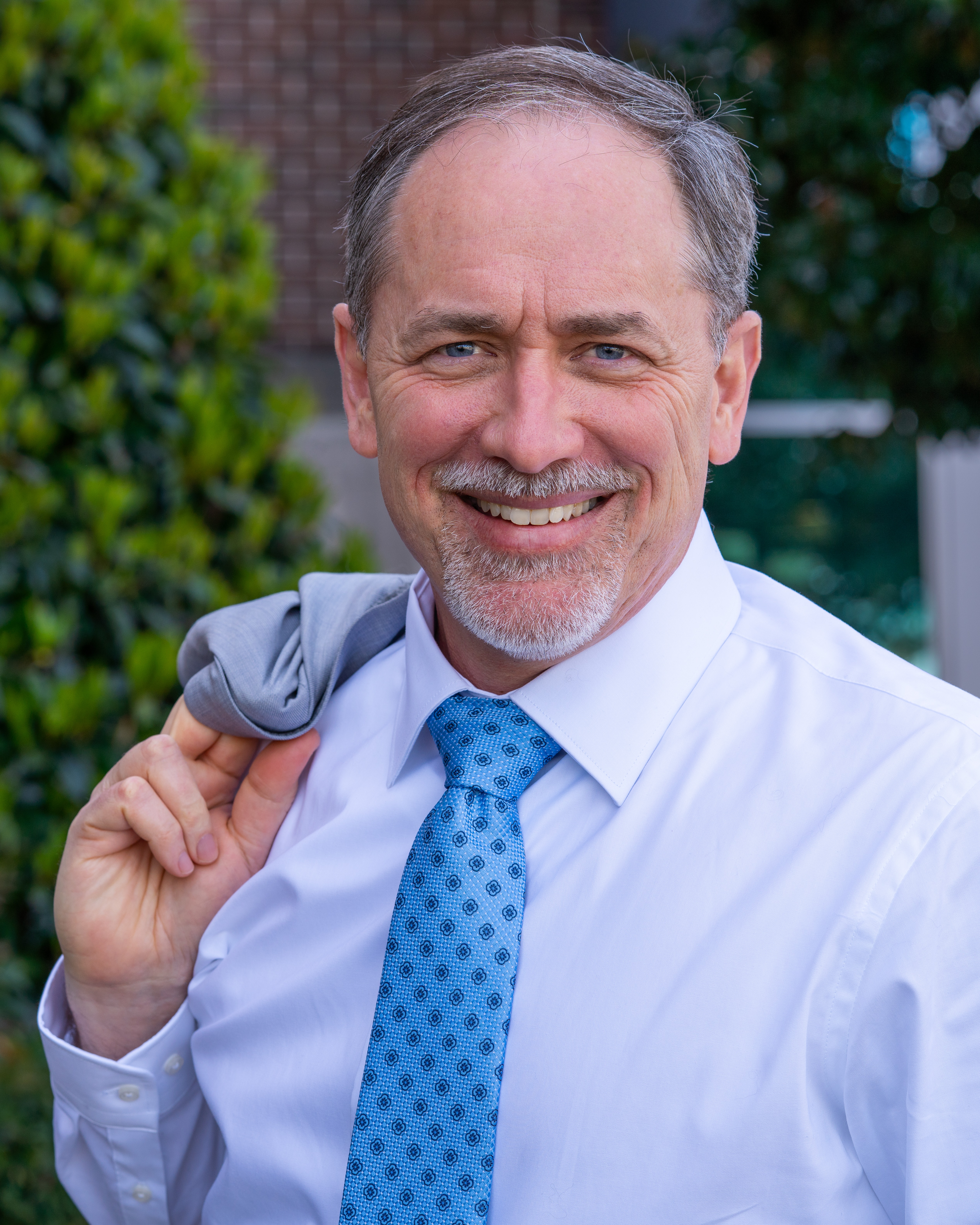 Dr. Brian Smith, smiling and holding his jacket.